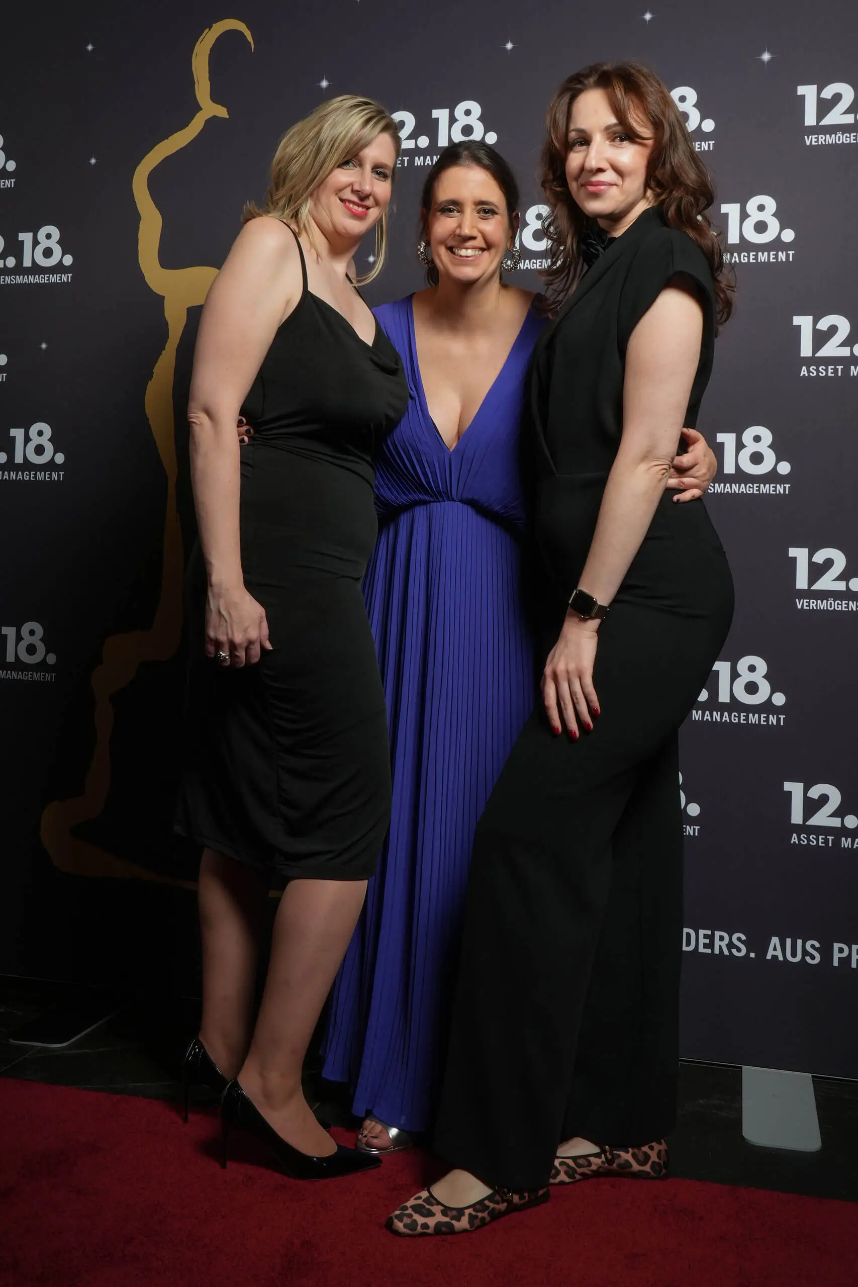 Drei Frauen in eleganten Kleidern bei einer glamourösen Veranstaltung.