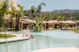 Frau sitzend in einem Pool umgeben von Palmen in einer Kurstadt, symbolisiert eine entspannende Auszeit