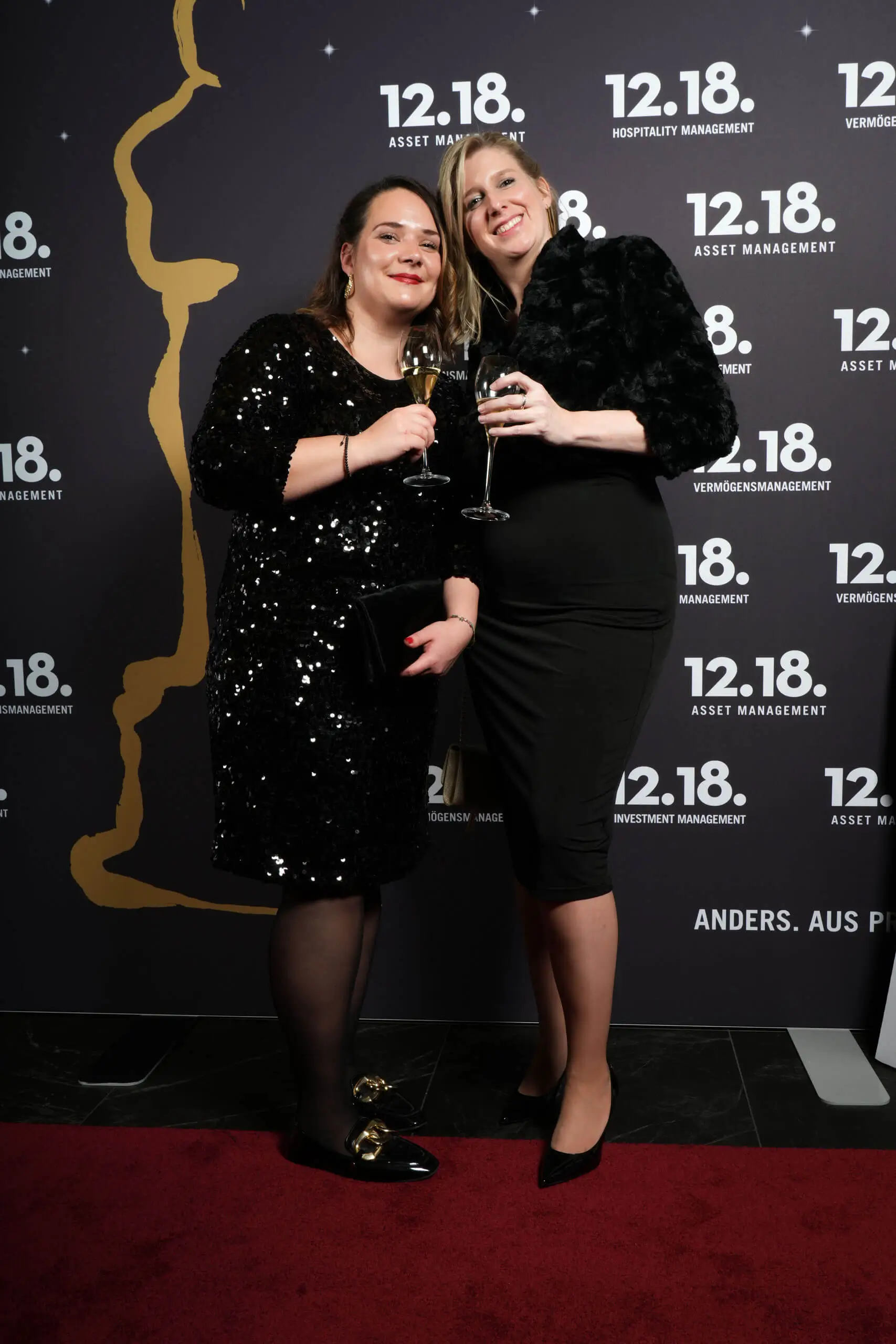 Zwei elegant gekleidete Frauen, die bei einer Veranstaltung mit Champagner feiern.