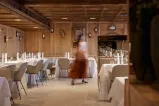 A woman walking in a restaurant with multiple chairs and Sonens Lee and 322 text in the background