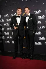 Two men in suits posing for a picture, with 12.18 Investment Management GmbH contextualized by the website address https://12-18.com
