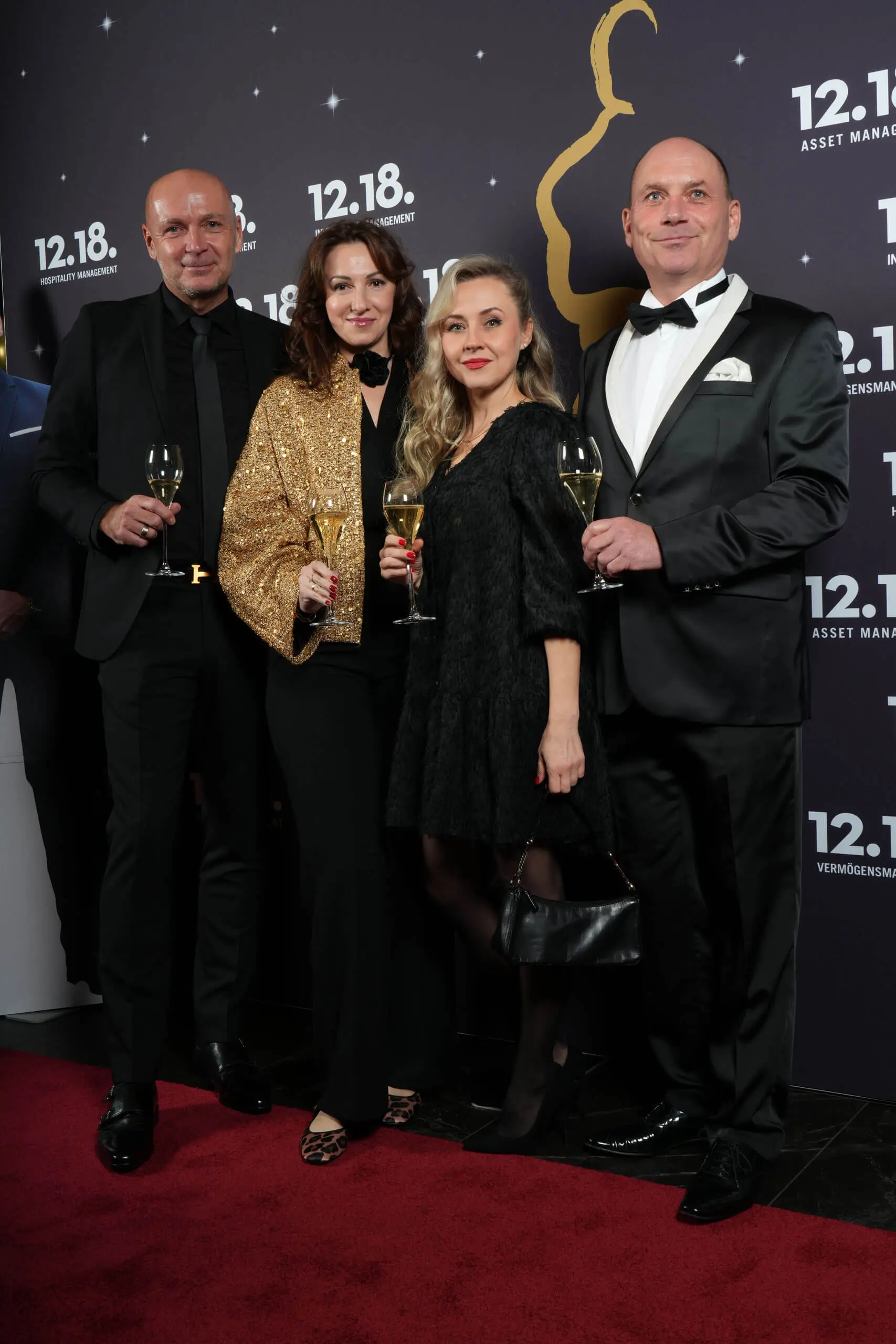 Elegante Gäste feiern mit Champagner bei der 12.18 Asset Management Veranstaltung.