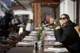 Frau sitzt in touristischem Restaurant mit Brille und Getränk am Tisch