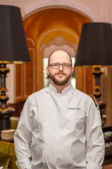 Chef Christian Braun im eleganten Hotelinterieur mit stilvollen Lampen.