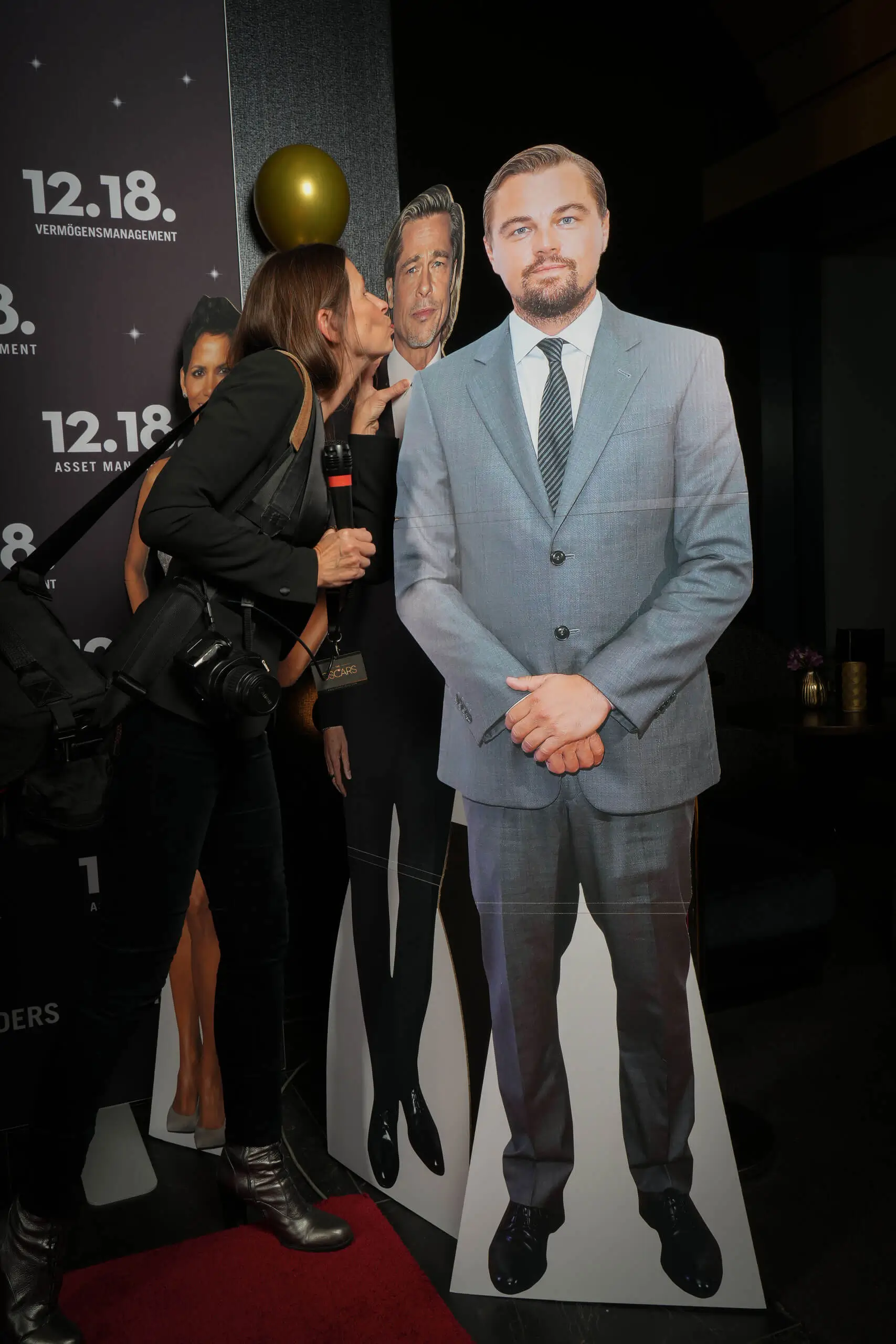 Eine Frau küsst einen lebensgroßen Cut-out eines Mannes im Anzug.