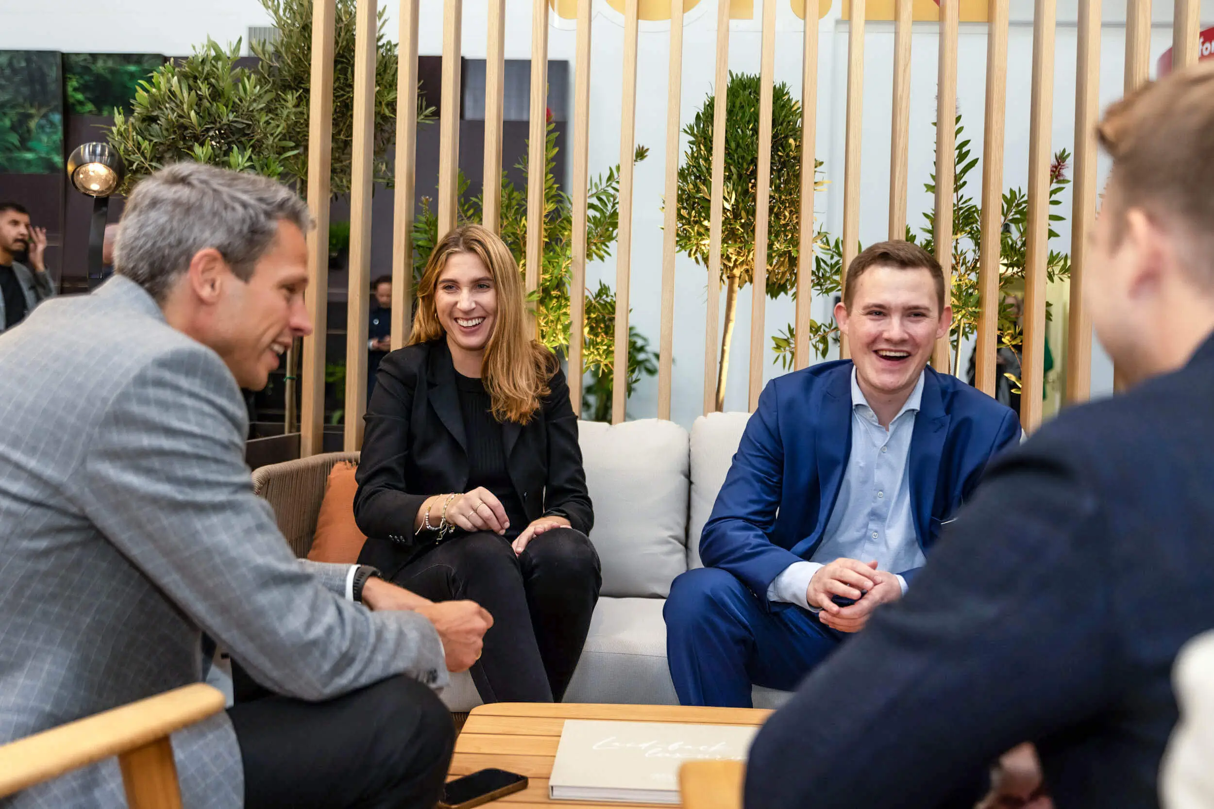 Vier Fachleute diskutieren gemeinsam in einer modernen Lounge auf einem Sofa.