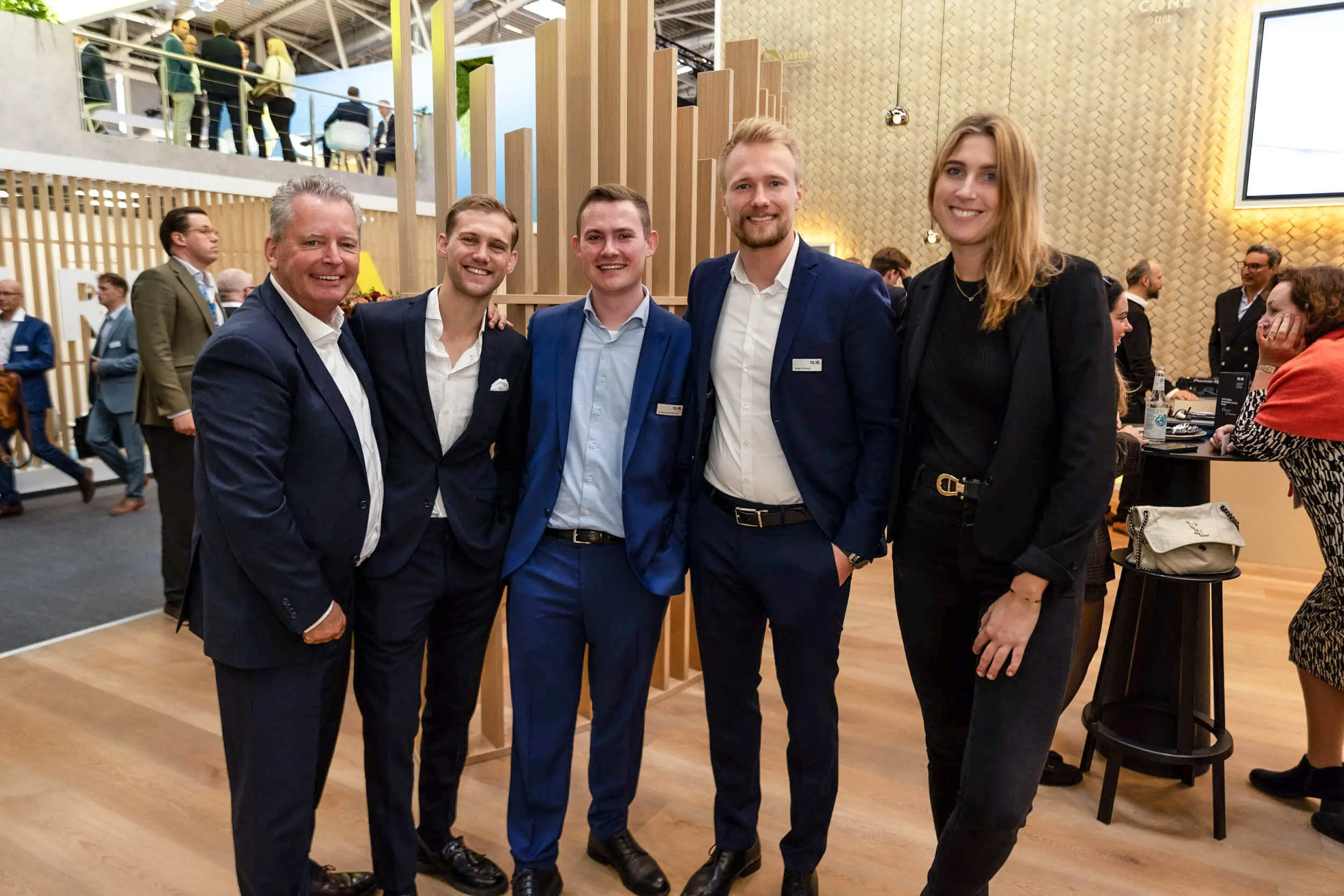 Fünf professionell gekleidete Personen posieren auf einer Networking-Veranstaltung.