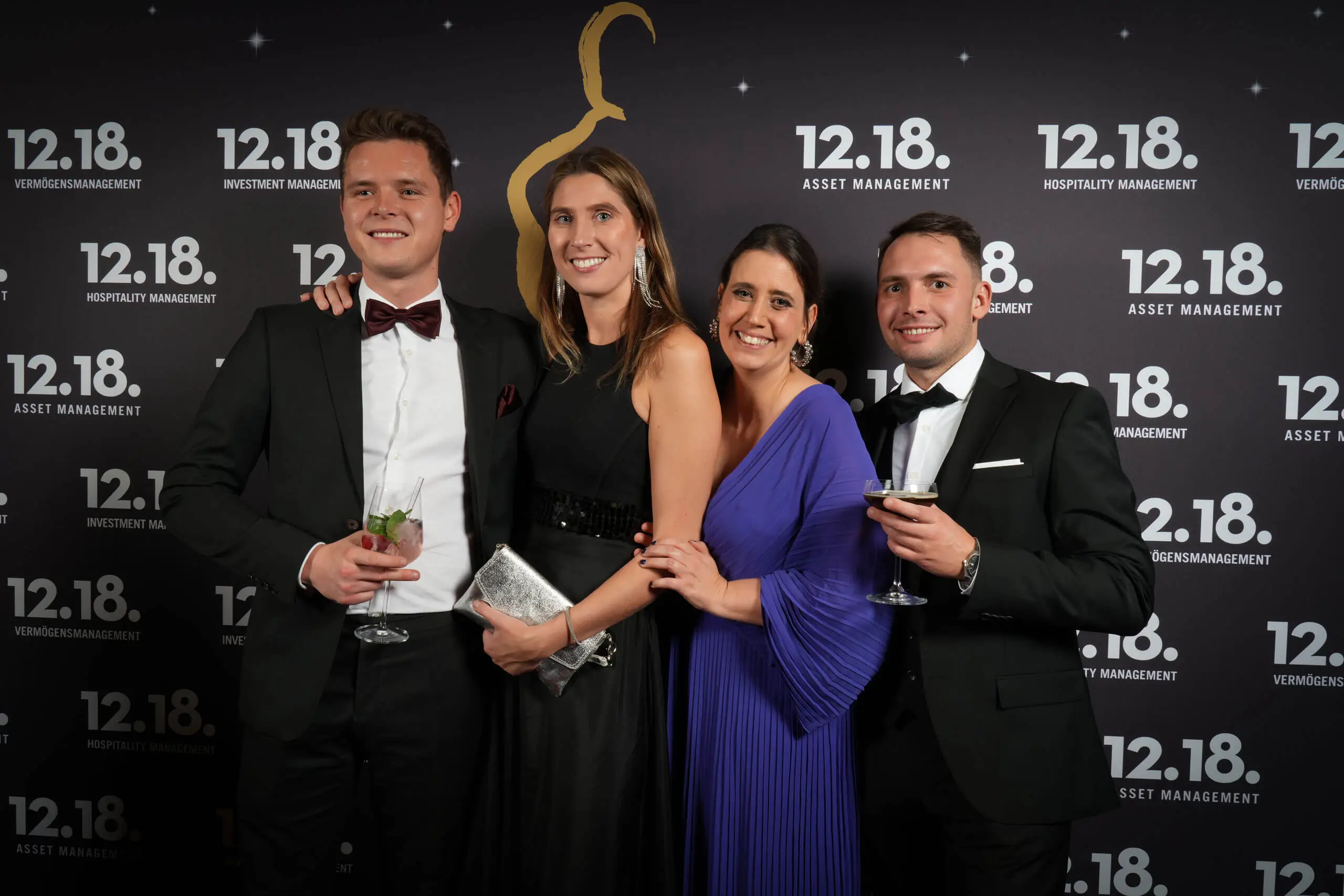 Vier elegant gekleidete Personen bei einer Firmenveranstaltung, die Gastfreundschaft und Feierlichkeiten zeigen.