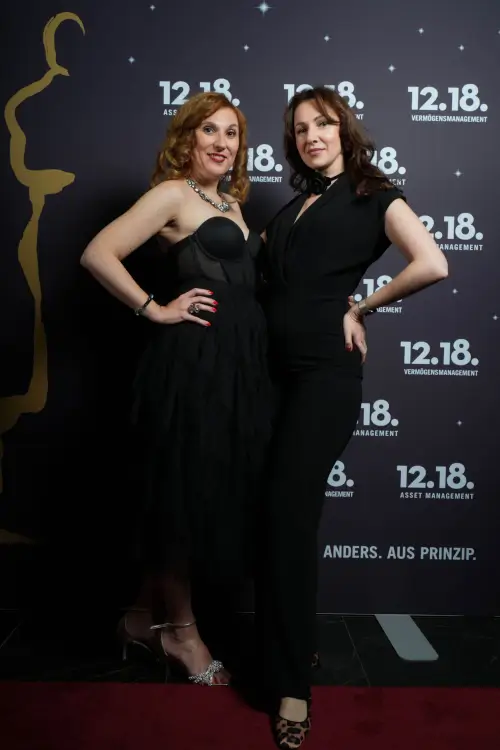 Zwei Frauen in eleganten Outfits bei einer glamourösen Veranstaltung.