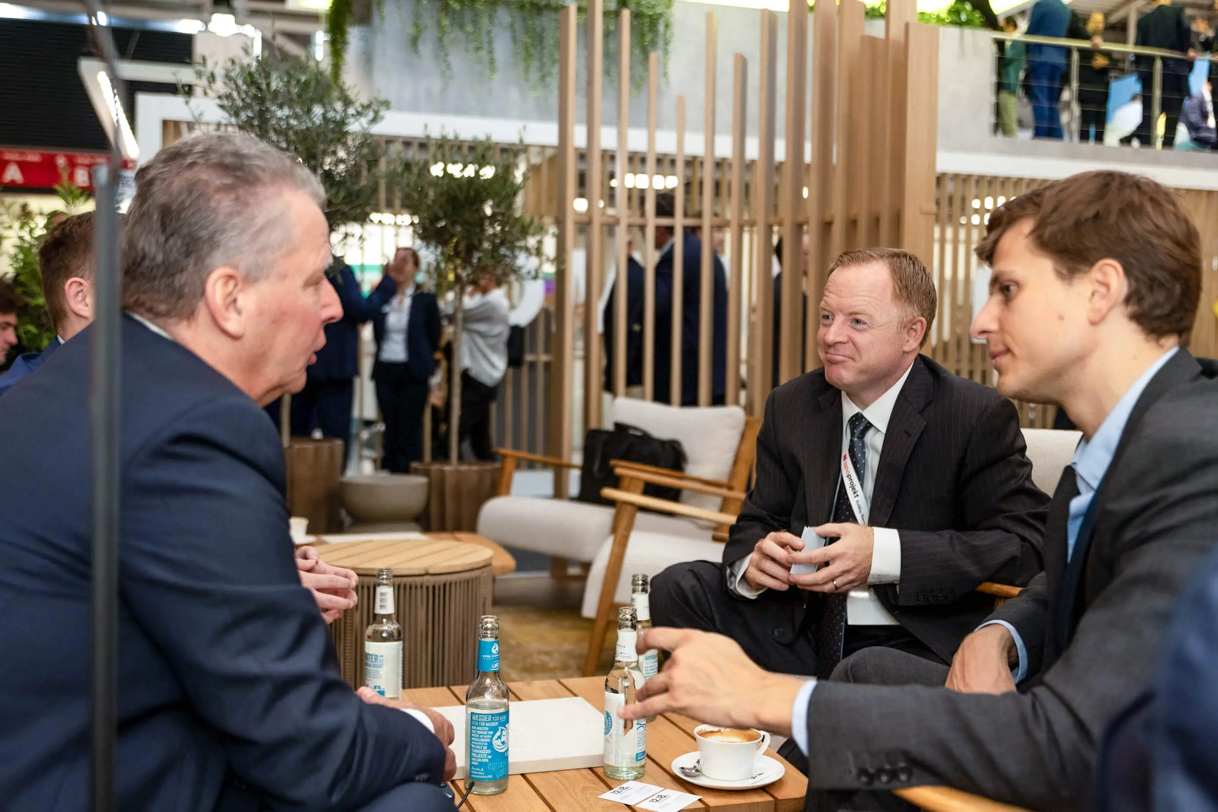 Vier Geschäftsleute unterhalten sich an einem Tisch auf einer Messe.