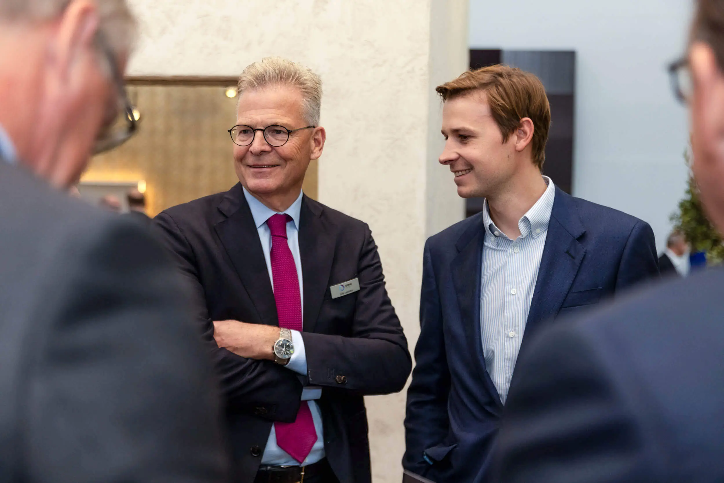 Zwei Männer im Business-Outfit unterhalten sich auf einer Fachveranstaltung.