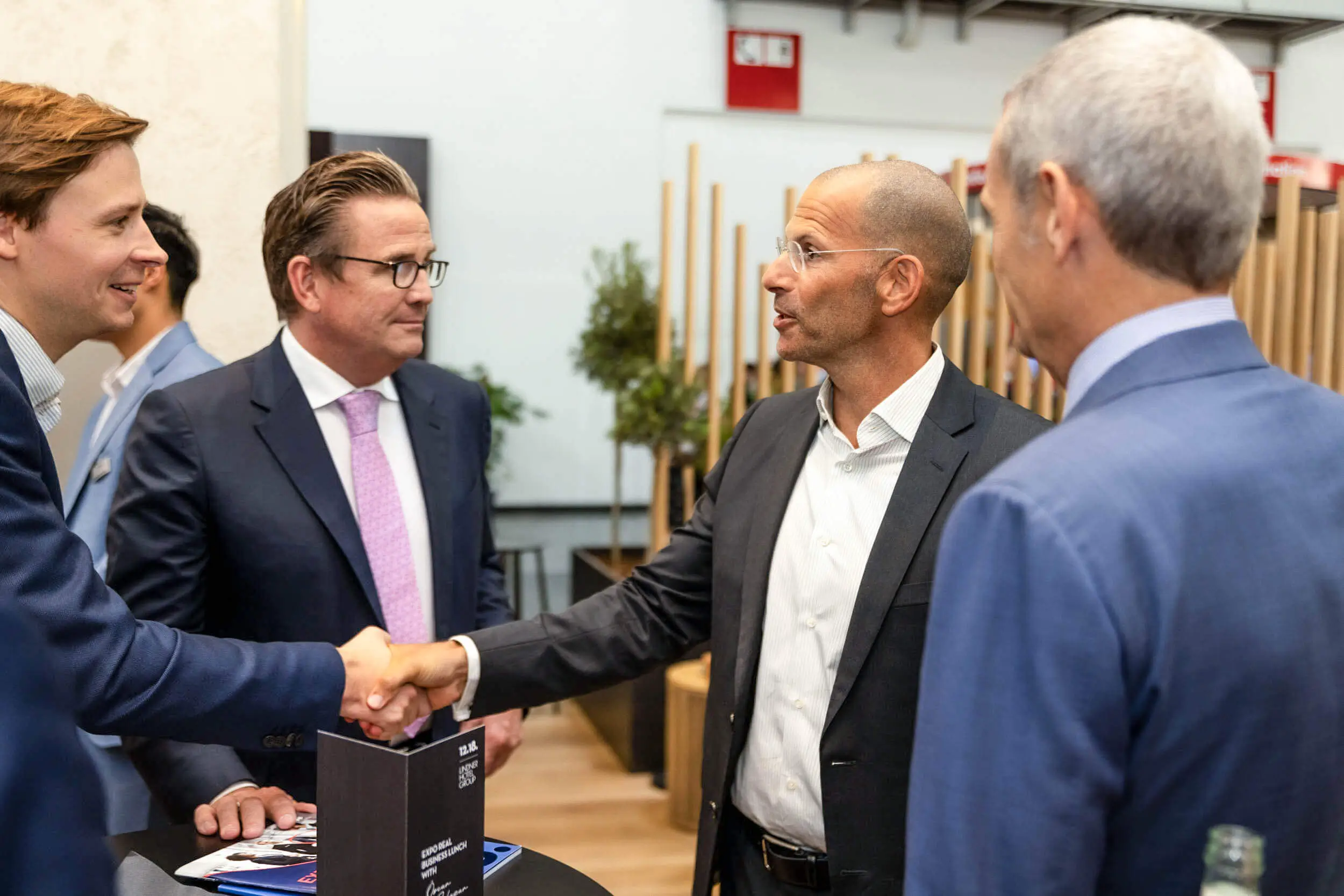 Professionelle beim Networking auf einer Messe mit Handschlag.