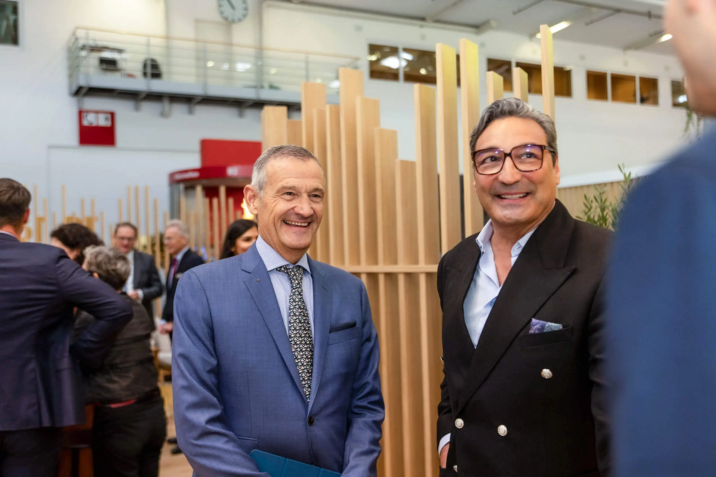 Zwei Männer lächeln und unterhalten sich bei einem Networking-Gespräch auf einer Expo.