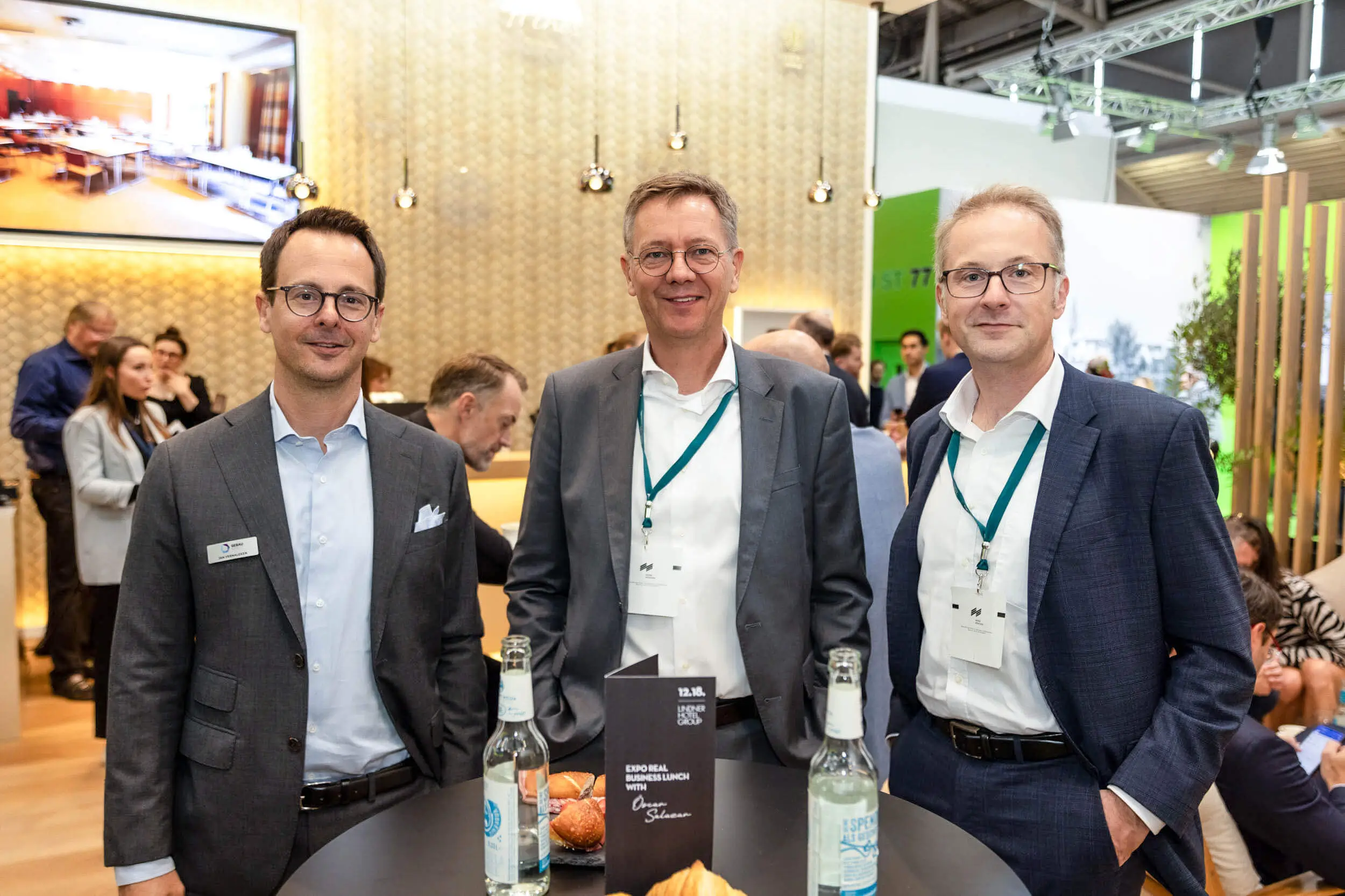 Drei Geschäftsleute an einem Messestand bei einer Networking-Veranstaltung.