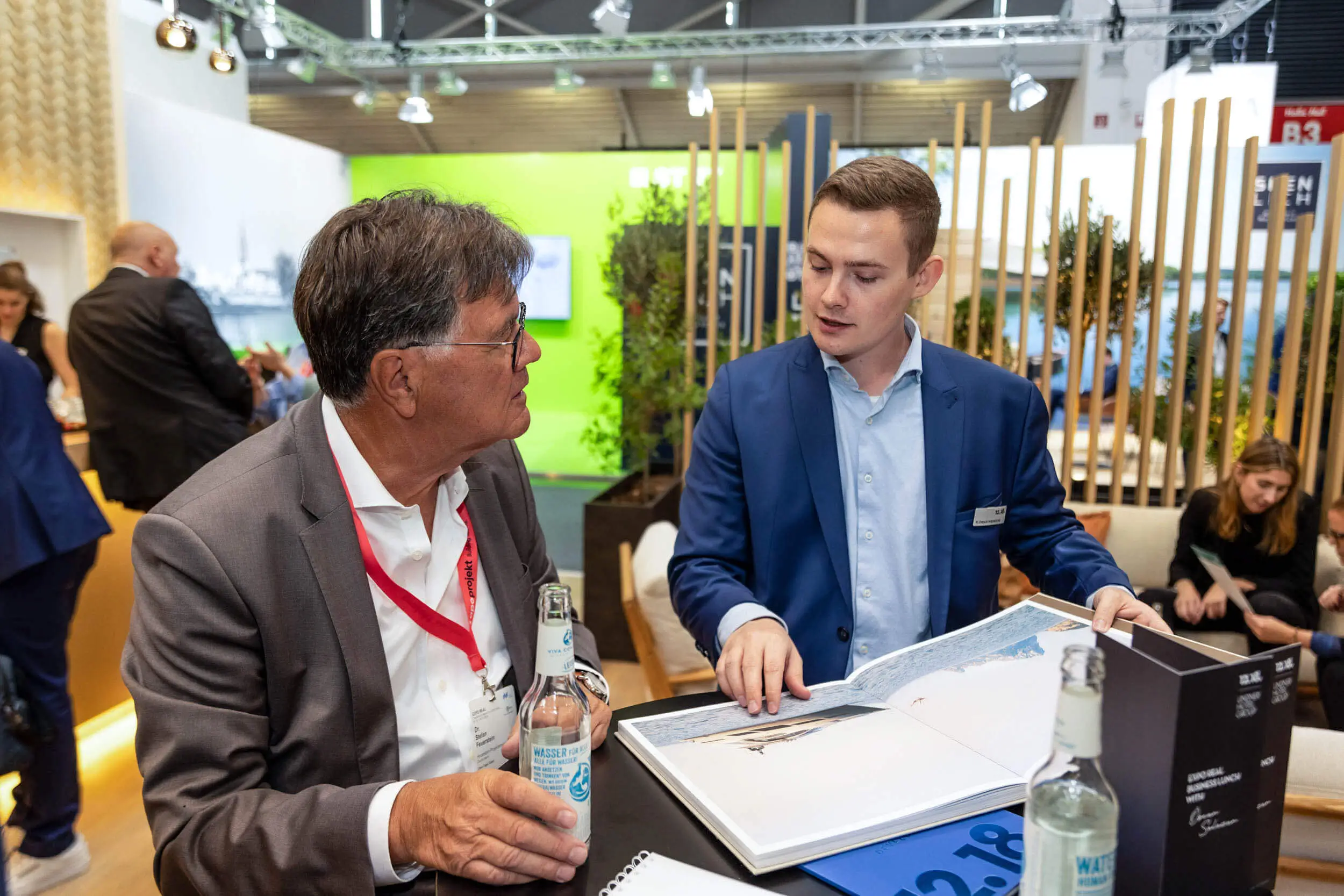 Zwei Männer besprechen Unterlagen an einem Messestand.