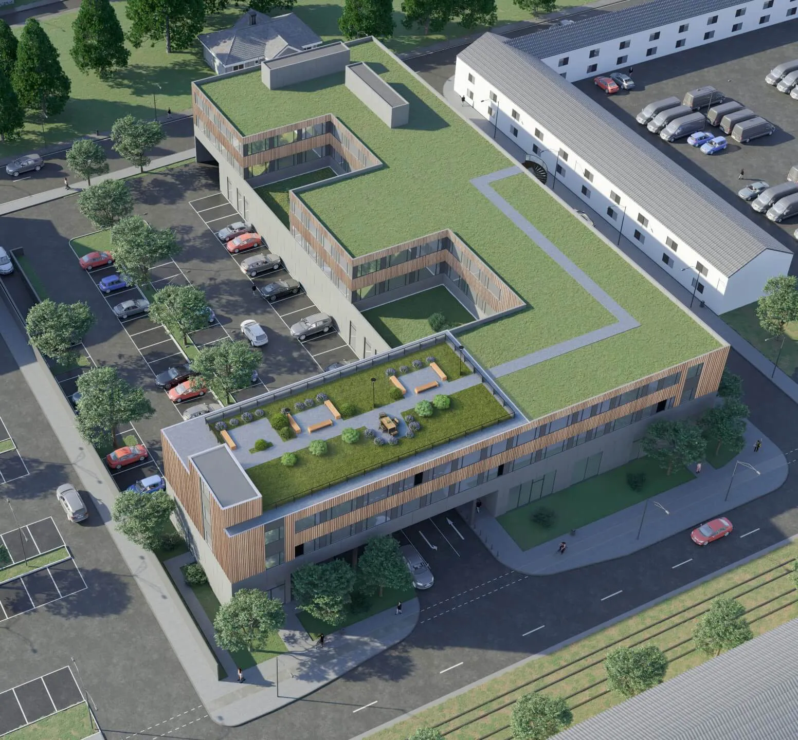 Moderne Gebäude mit grünem Dach, umgeben von Parkplätzen und Bäumen.