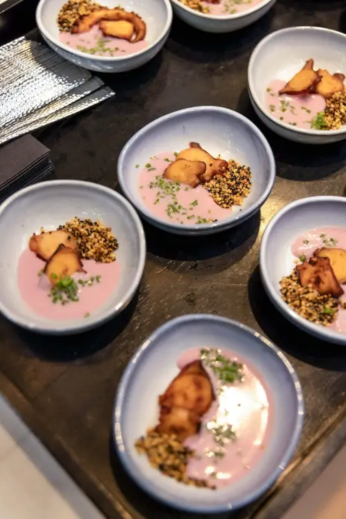 Gourmet-pinkes Essen mit Frucht- und Saatgarnierungen in eleganten Schalen serviert.