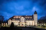 Das historische Hotelgebäude bei Nacht, beleuchtet, im städtischen Umfeld.