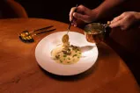 Person holding a spoon over a plate of food in a restaurant