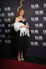 Eine lächelnde Frau in einem Kleid, die ein Glas Champagner auf der Veranstaltung von 12. 18. Investment Management GmbH hält