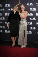 Two smiling women posing for a photo in formal dresses at a premiere event