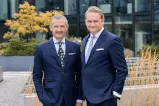 12.18. Group founders Jörg Lindner & Kai Richter in suits, posing in front of a building.
