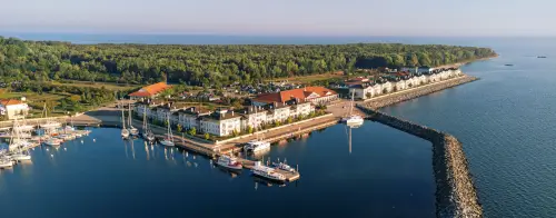 Eine malerische Marina mit Booten und Wohngebäuden am Ufer, umgeben von Grünflächen.