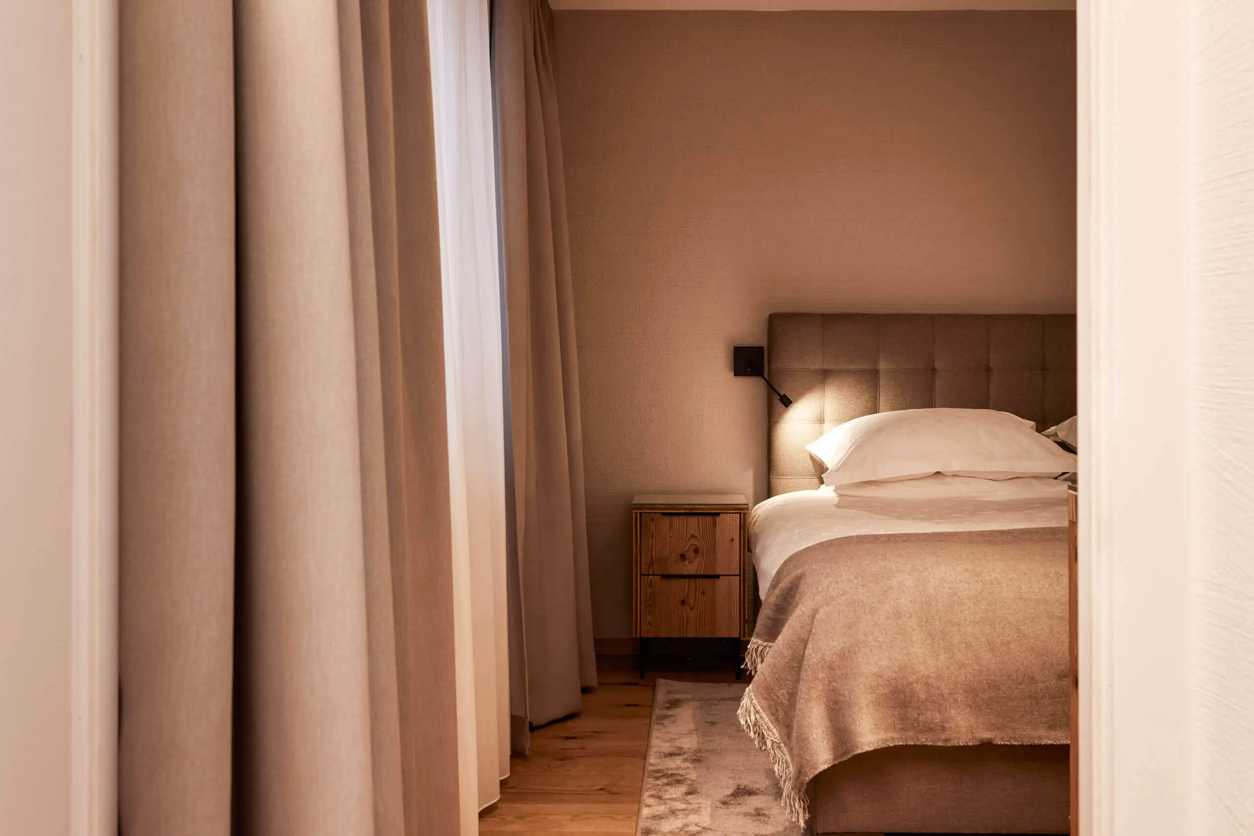 Cozy modern bedroom featuring a bed, nightstand, and soft curtains.