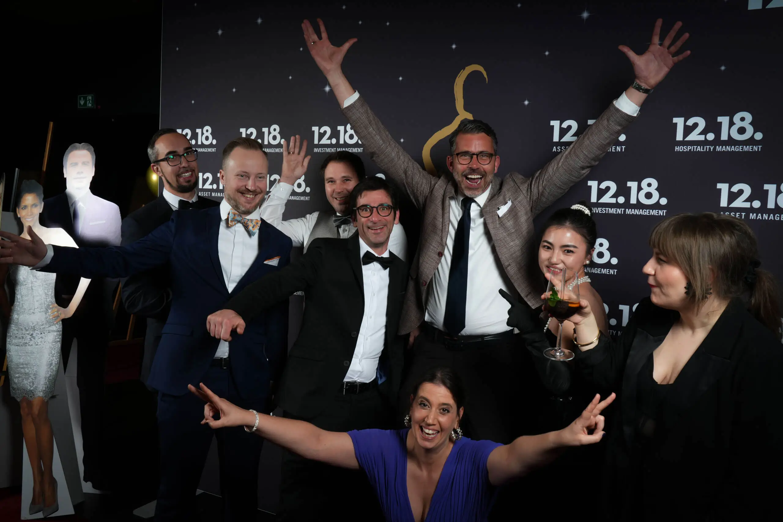 Eine lebhafte Gruppe feiert mit Freunden und einem Pappaufsteller bei einer Veranstaltung des Hotelmanagements.