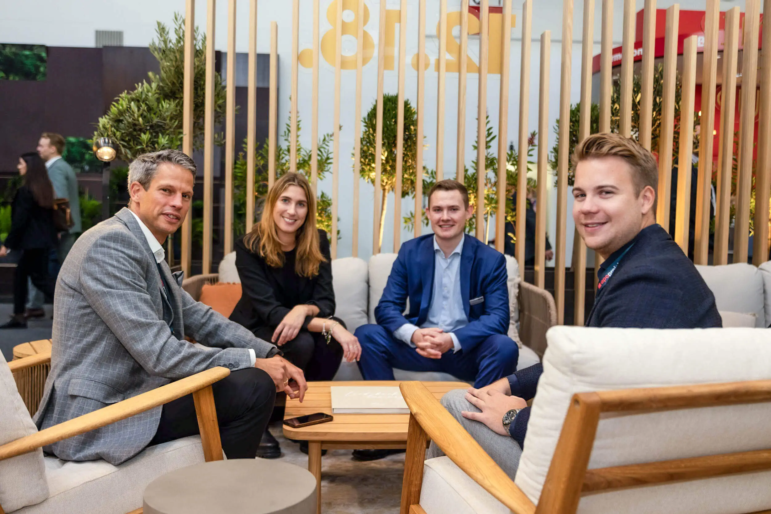 Vier Fachleute sprechen in einer modernen Lounge auf einer Messe.