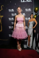 A woman in a pink dress presenting the 12.18. Investment Management GmbH on a website.