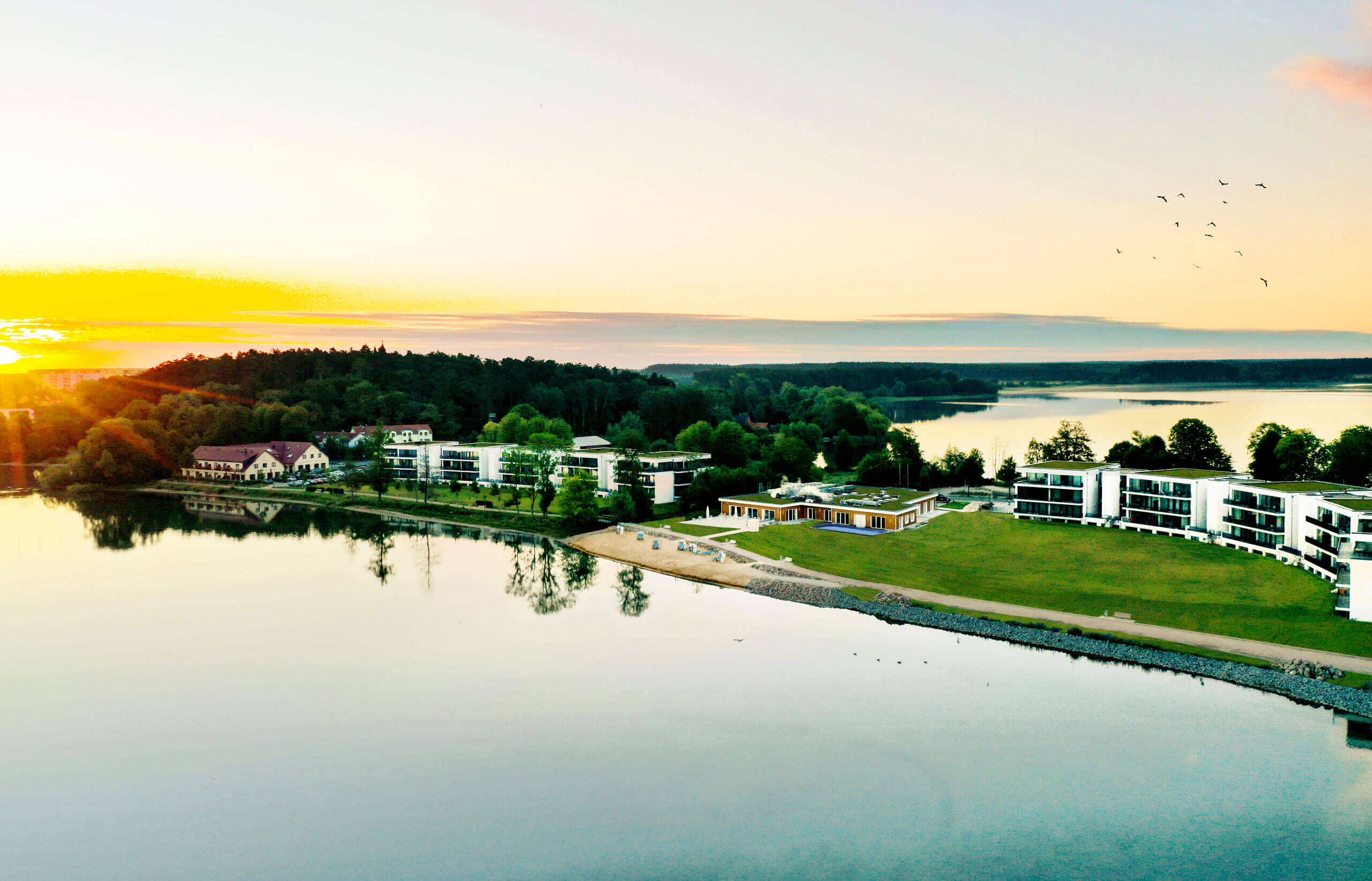 A serene landscape of Maremüritz Yachthafen Resort & Spa nestled by a body of water and vibrant