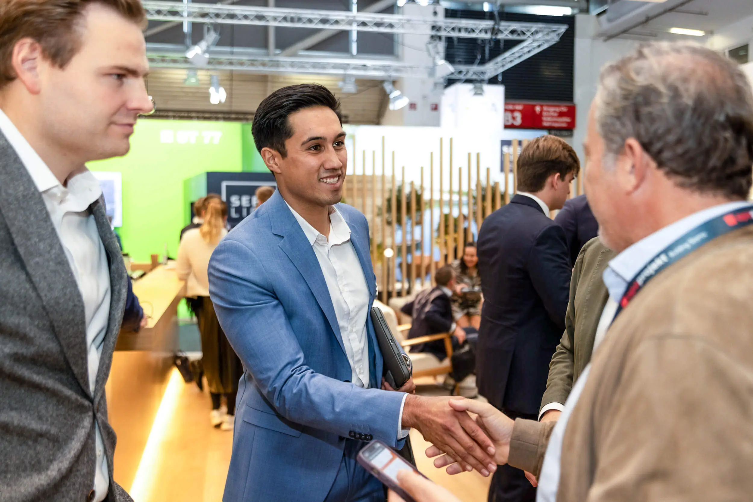 Auf einer Fachmesse begrüßen sich zwei Geschäftsleute mit einem Handschlag.