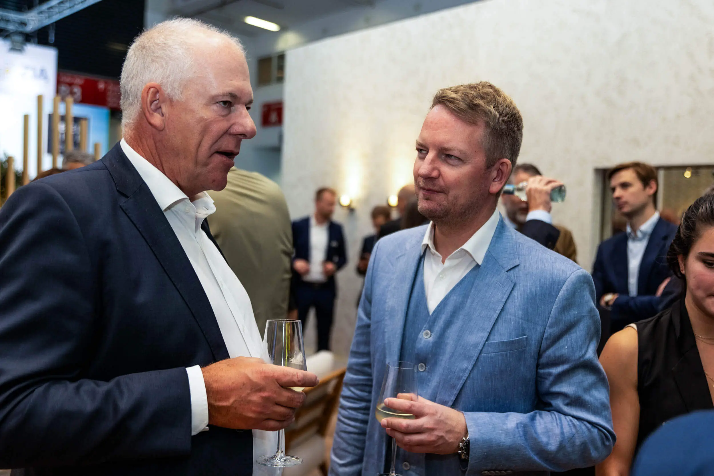 Zwei Männer, die während einer Veranstaltung mit Getränken netzwerken und professionelle Interaktionen betonen.