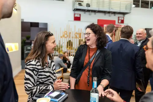 Zwei Frauen diskutieren auf einer Networking-Veranstaltung und zeigen geschäftliche Interaktionen und Kameradschaft.