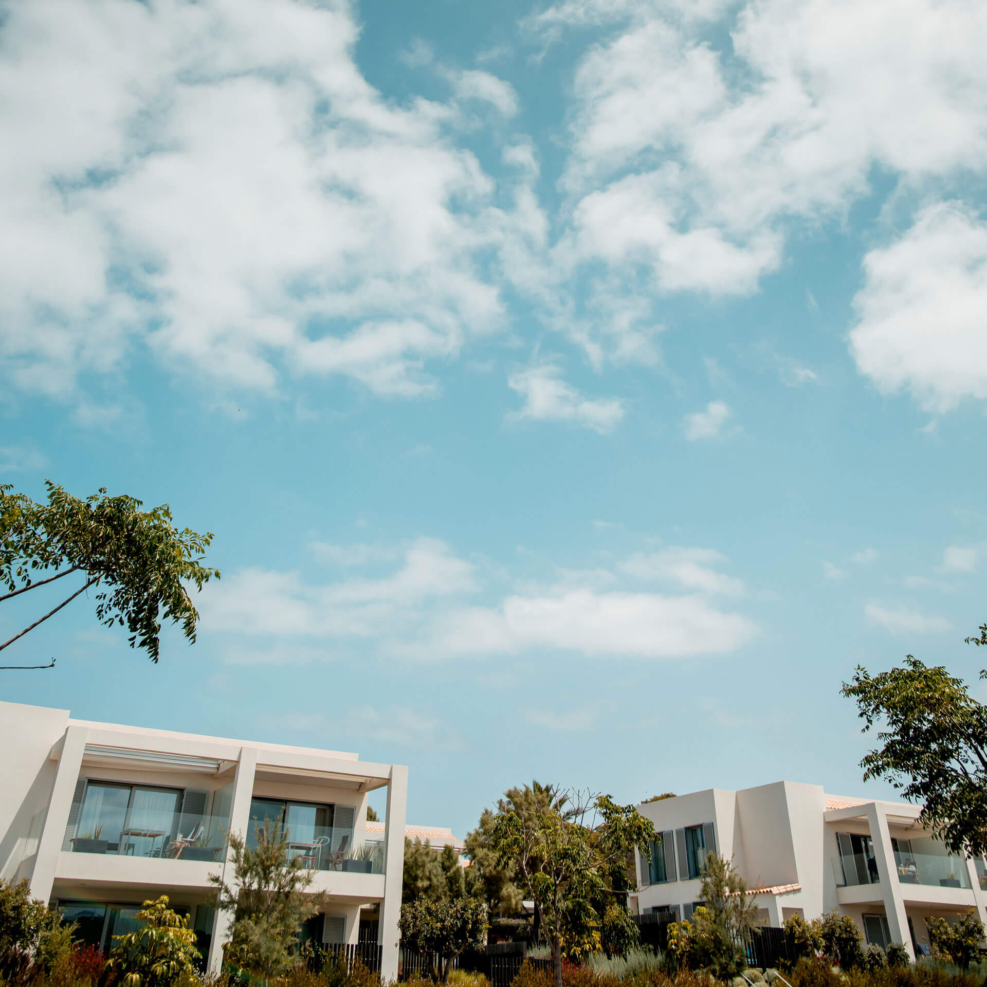 Eine Gruppe weißer Gebäude mit Bäumen und blauem Himmel, die die von der 12.18. Investment Manage