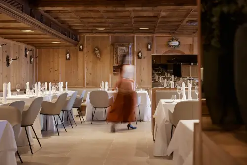 Elegante Restaurant-Interieur mit Holzdekor und einer Person, die Gäste bedient.