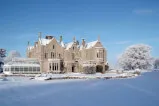 Schloss im Winter, umgeben von Schnee und Natur.