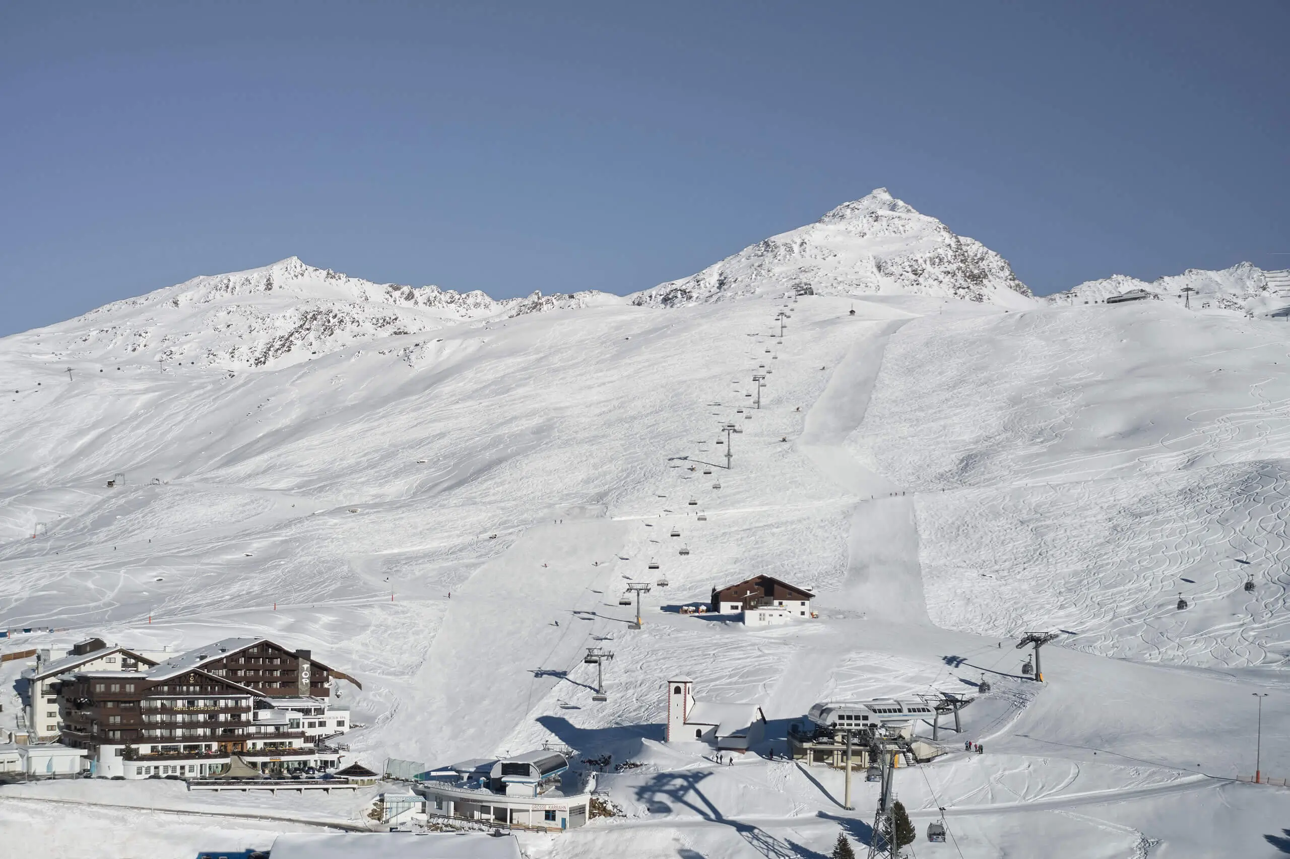 Hotel in der Schneelandschaft eines Skiresorts mit Berg und Skilift.