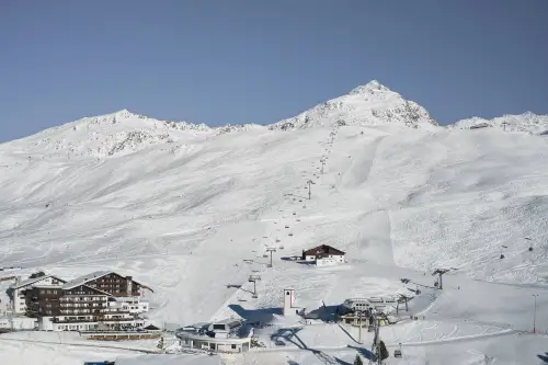 Schneebedeckte Berge und Skilifte über einem Hotel in einem Skiort.