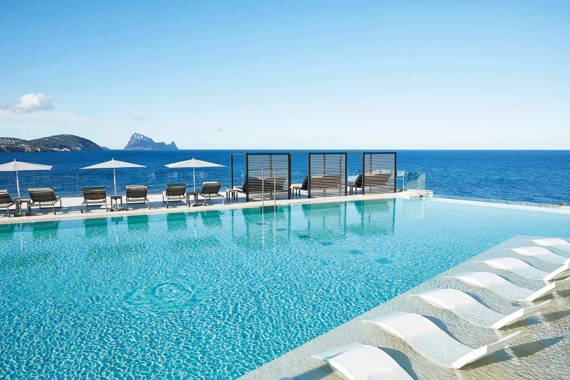 Luxurious pool with ocean view and sun shades in a tourist real estate complex.