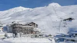 Hotel in einer schneebedeckten Berglandschaft mit Skilift.