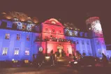 Beleuchtetes historisches Gebäude bei Nacht mit festlichem Ambiente.