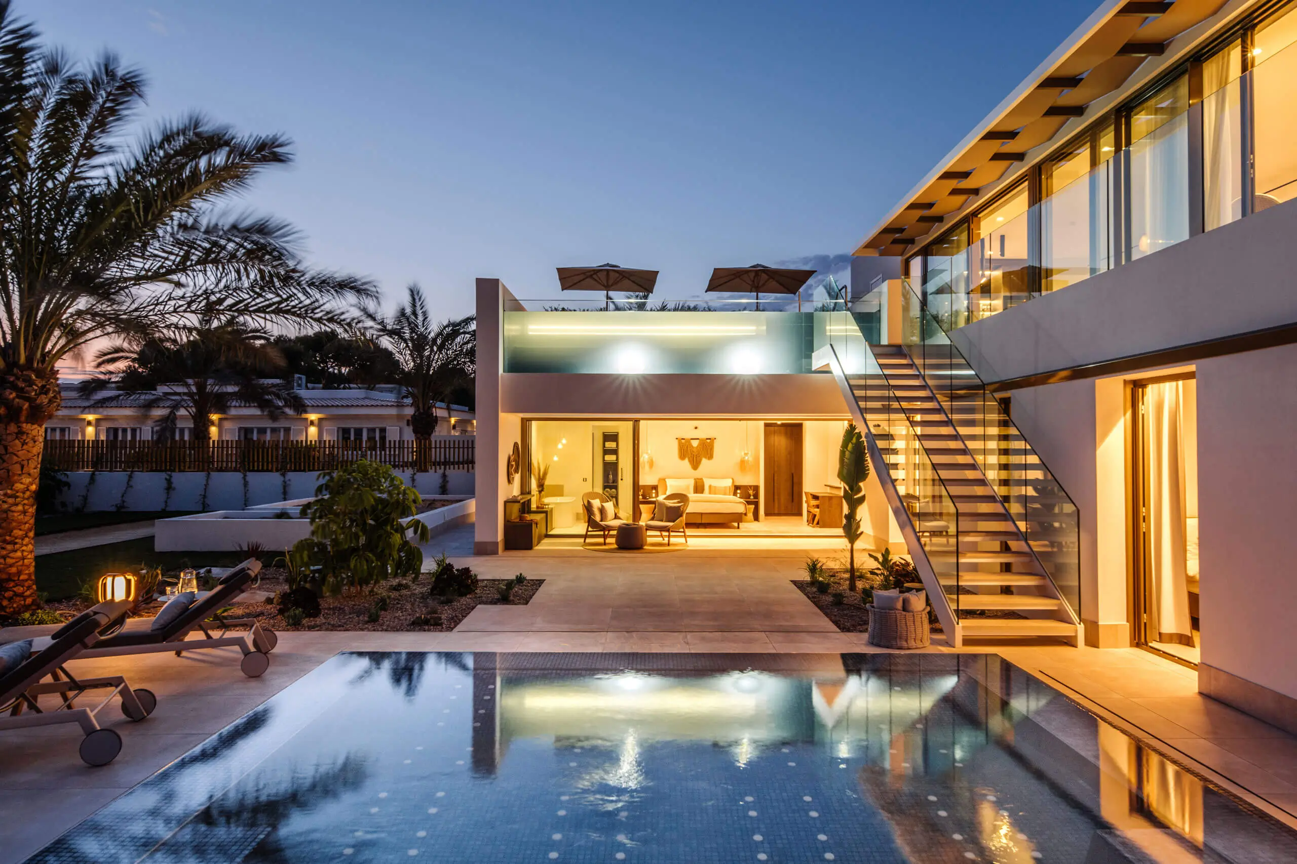 Moderne Villa mit Pool und Palmen, die luxuriöses Wohnen zeigt.