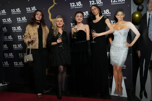 Vier elegante Frauen feiern bei einer Vermögensverwaltungsveranstaltung, mit einem Prominenten-Pappaufsteller im Hintergrund.