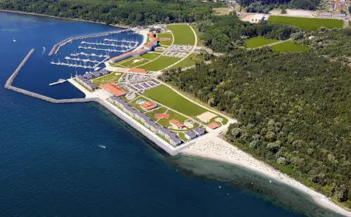 Luftaufnahme eines Yachthafens mit grünem Park, Wasser und Sandstrand.